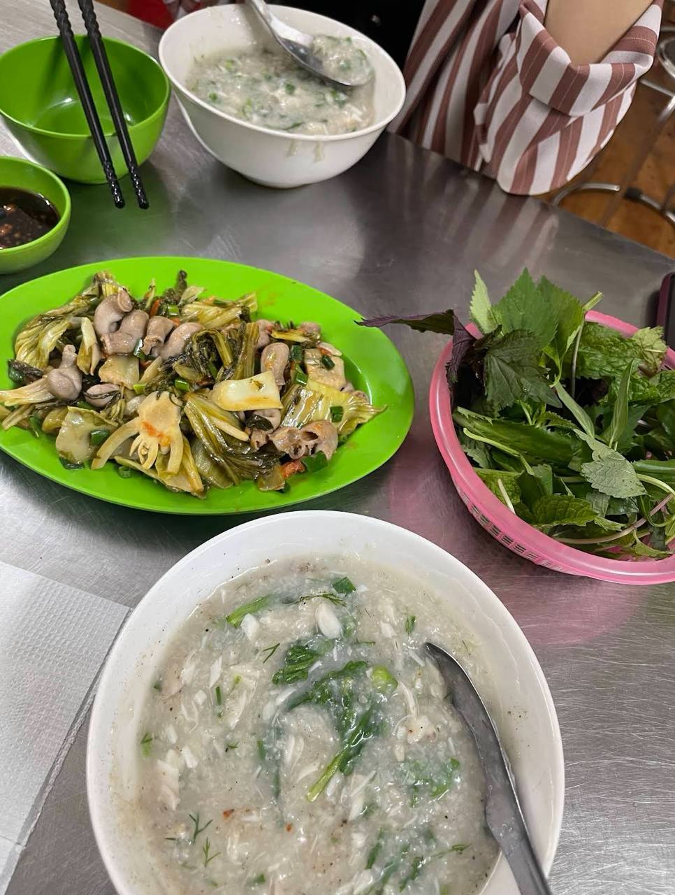 Nhiều người gọi thêm một đĩa dạ dày cá xào dưa chua và vài cốc bia, biến bữa cháo đêm thành một cuộc lai rai đúng kiểu hàng quán phố cổ. Ảnh: Google Review