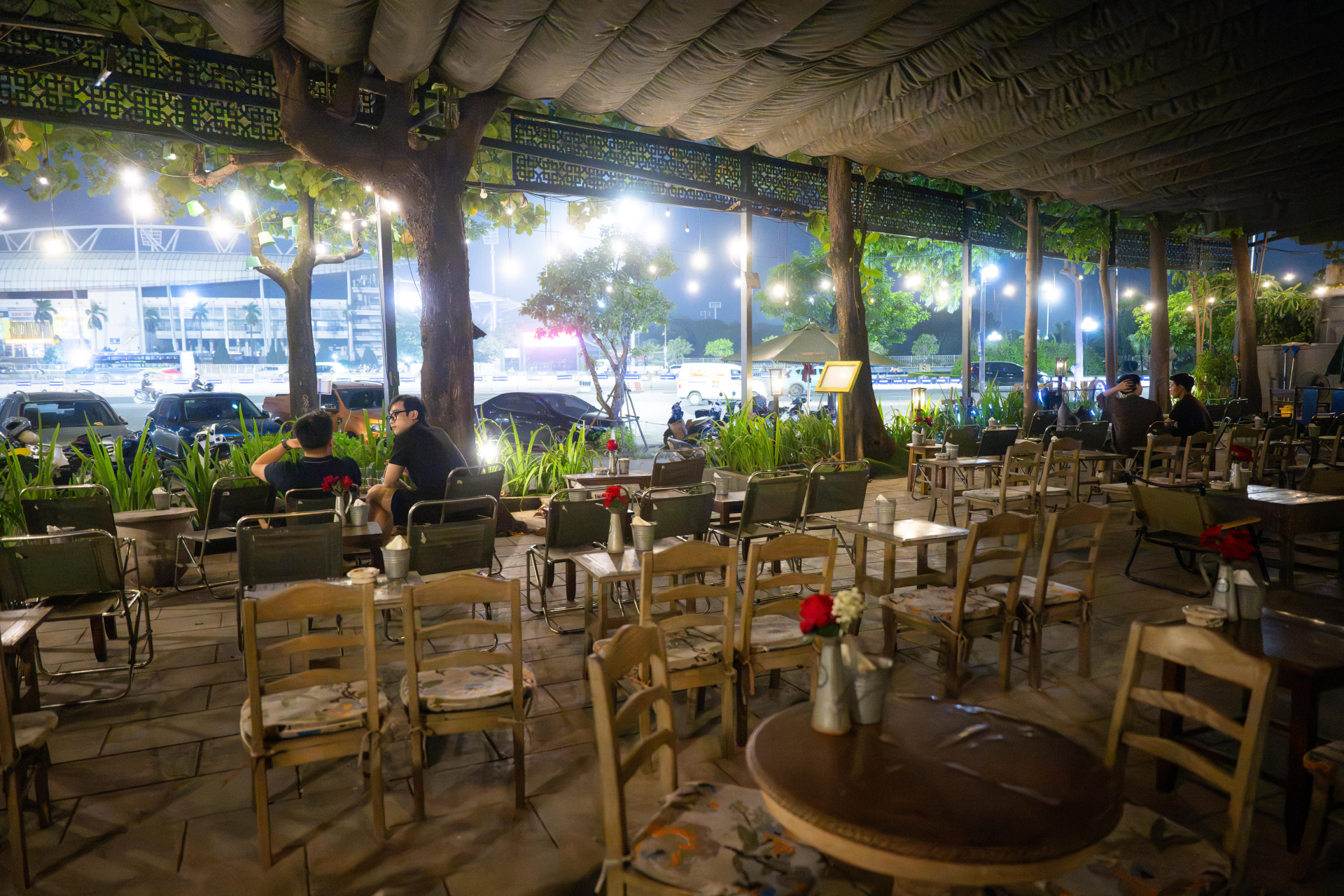 Ở một quán cà phê, dãy ghế ngoài trời giăng đèn lung linh còn bỏ trống khá nhiều, khách chỉ ngồi rải rác vài bàn.
