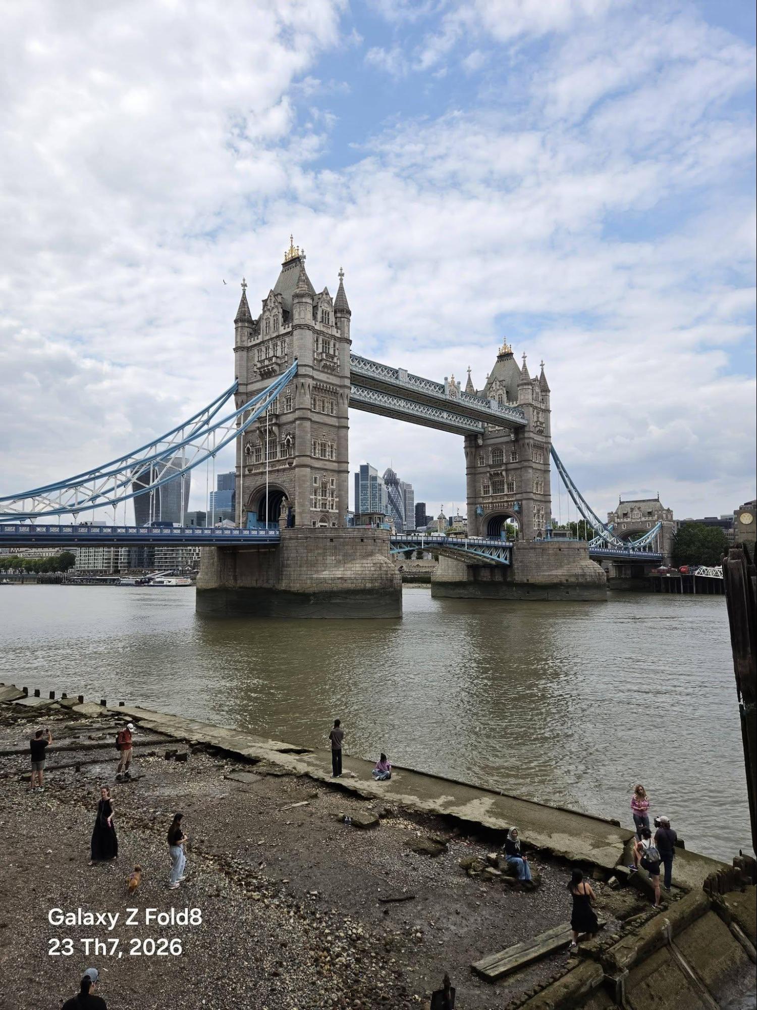 Bãi bồi lộ ra khi thủy triều rút là chỗ chụp Tower Bridge đẹp nhất, và cũng là chỗ luôn có người. Ảnh giữ đúng sắc nâu đục của nước sông thay vì kéo sang xanh cho bắt mắt, nhưng trong khung có hơn chục người đứng rải rác ở tiền cảnh.