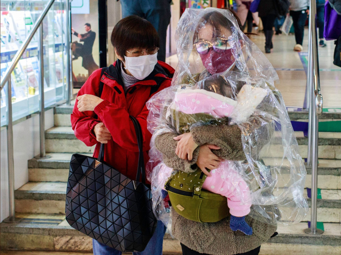 Người phụ nữ bế con được chùm trong miếng nhựa đi dạo trên đường phố Hồng Kong (Ảnh: Kevin On Man Lee/Penta Press/REX/Shutterstock).