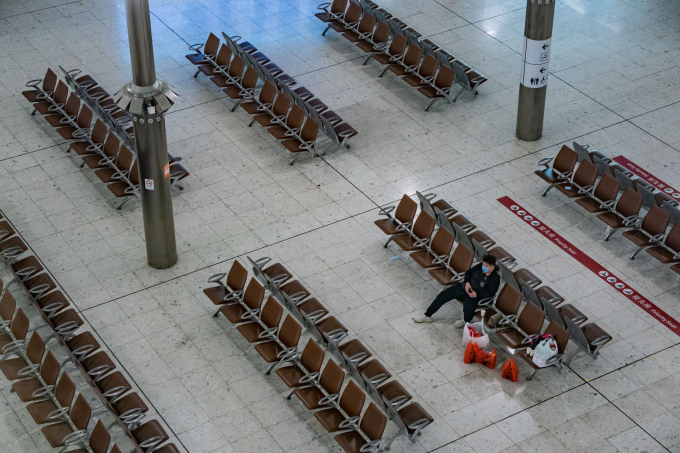   Một người đeo khẩu trang ngồi chờ tàu một mình trong nhà ga vắng tanh (Ảnh: Anthony Kwan/Getty Images).  