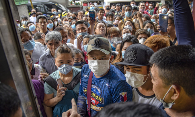 Người dân Philippines chen nhau mua khẩu trang bên ngoài một hiệu thuốc. Chính quyền nước này đang cố gắng tìm kiếm những người đã từng tiếp xúc với ca tử vong đầu tiên tại nước này (Ảnh: Photograph: Ezra Acayan/Getty Images).