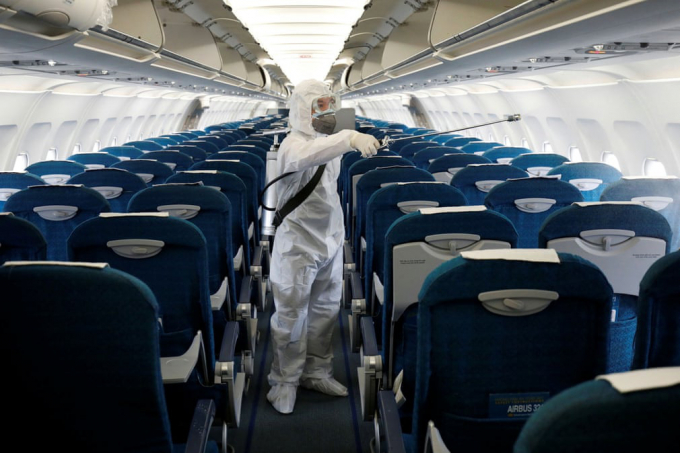Nhân viên y tế phun thuốc khử trùng trên một chuyến bay của hãng hàng không Vietnam Airlines tại sân bay Nội Bài (Ảnh: Reuters).