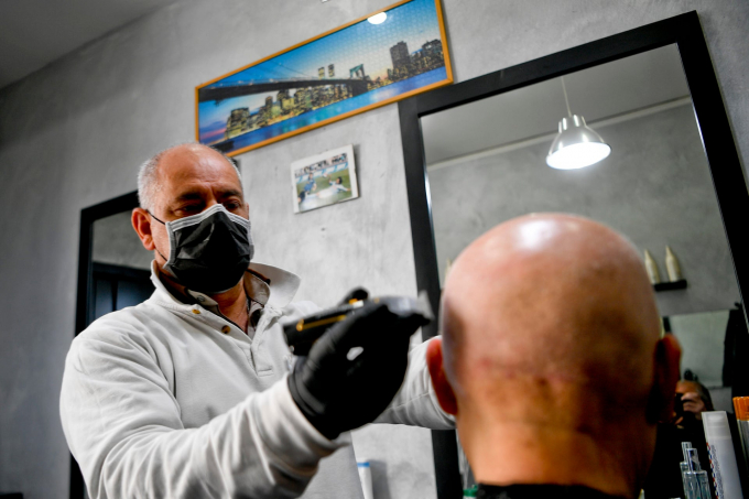 Một thợ cắt tóc đeo khẩu trang và găng tay khi làm việc tại Naples (Ảnh: Ciro Fusco/EPA).