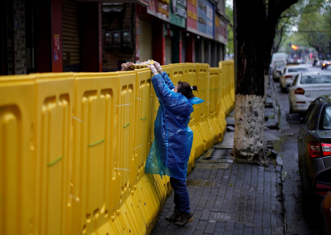   Vũ Hán, Trung Quốc: Một phụ nữ đưa trứng cho người bên kia rào chắn (Ảnh: Aly Song/Reuters)  