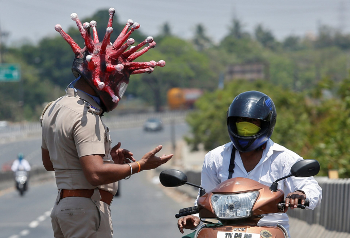   Chennai, Ấn Độ: Sĩ quan cảnh sát Rajesh Babu đội một chiếc mũ bảo hiểm hình virus corona khi buộc người dân phải tuân thủ lệnh phong tỏa của quốc gia (Ảnh: P Ravikumar/Reuters).  
