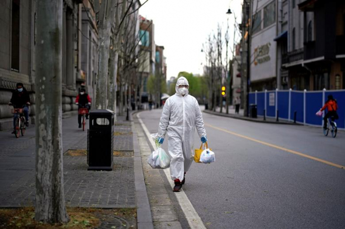 Một người đàn ông mặc trang phục bảo hộ đi trên đường ở Vũ Hán hôm 28/3 (Ảnh: Reuters/ Aly Song).