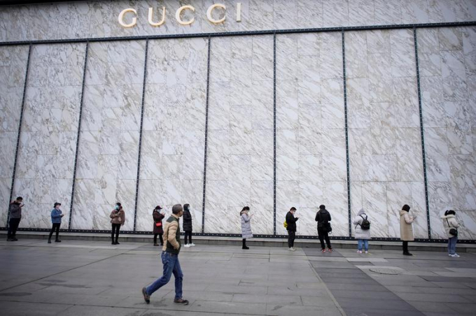 Người dân đeo khẩu trang xếp hàng để vào một trung tâm thương mại bên ngoài một cửa hàng Gucci tại Vũ Hán hôm 30/3/2020 (Ảnh: Reuters/ Aly Song).