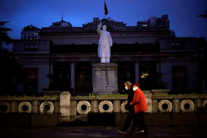 Đôi vợ chồng đi dạo trước bức tượng của chủ tịch Mao Trạch Đông trên một con đường ở Vũ Hán (Ảnh: Reuters/ Aly Song).