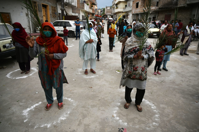 Các tín đồ Thiên chúa giáo đứng trong những vòng tròn vẽ trên mặt đất nhằm duy trì khoảng cách xã hội, cầm một nhánh cọ để kỷ niệm sự kiện lễ lá trong khi chính phủ đã áp đặt lệnh phong tỏa toàn quốc vì đại dịch (Ảnh: Aamir Qureshi | AFP | Getty Images).