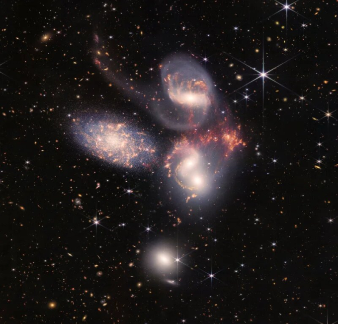 Một nhóm năm thiên hà xuất hiện gần nhau trên bầu trời: hai thiên hà ở giữa, một thiên về phía trên, một ở phía trên bên trái và một ở phía dưới (Ảnh:NASA, ESA, CSA, STScI).