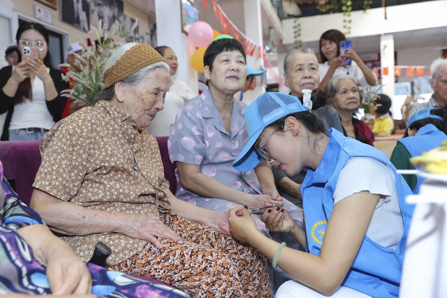 Tình nguyện viên bấm móng tay cho cụ bà tại viện dưỡng lão. (Ảnh: Mai Thuỳ)
