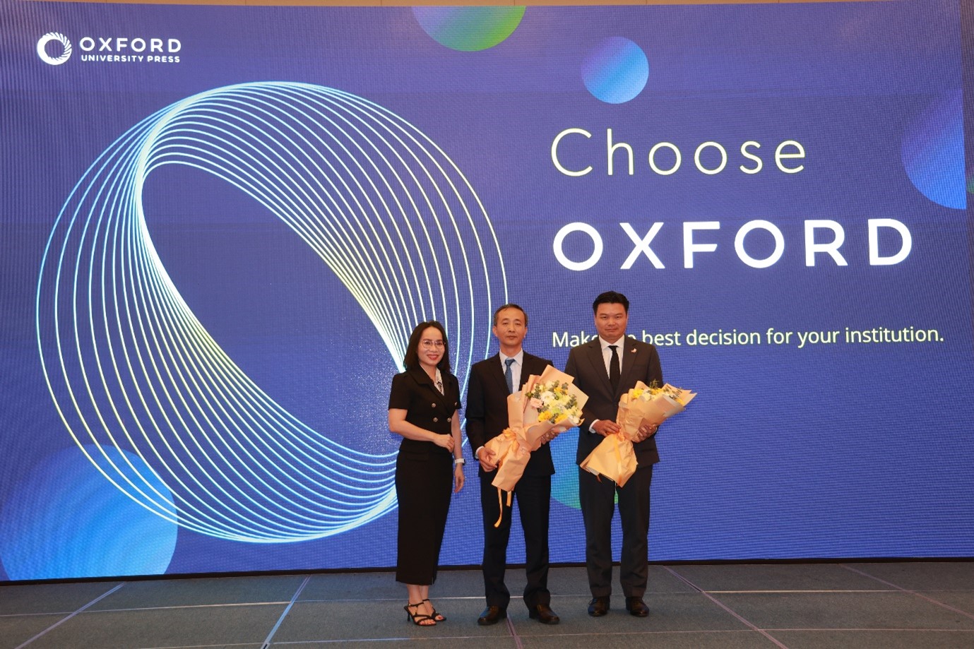 Bà Nguyễn Uyên - Trưởng Đại diện VP NXB Đại học Oxford tại Việt Nam tặng hoa cho ông Nguyễn Chí Bính – Phó Tổng giám đốc thường trực NXBGDVN và ông Hoàng Tùng - Giám đốc Công ty Cổ phần Giáo dục Quốc tế UKTA