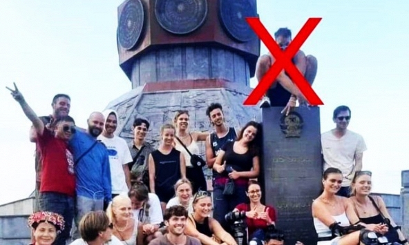 Bức xúc hình ảnh du khách nước ngoài ngồi lên lên tấm bia khắc hình Quốc huy ở Hà Giang