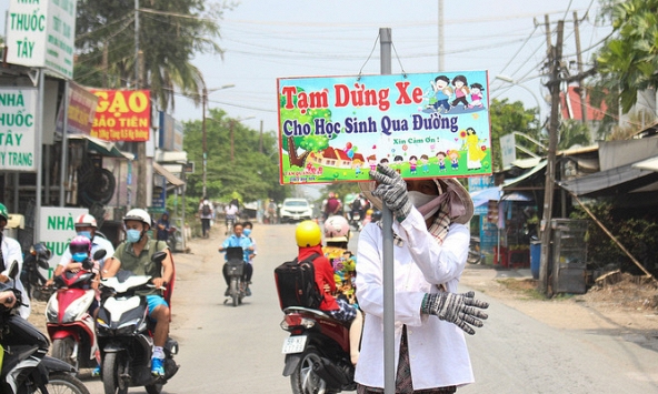 Người phụ nữ hằng ngày cầm biển chặn xe giúp học sinh qua đường 