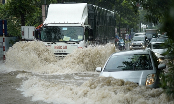 Người dân Hà Nội bì bõm sau cơn mưa lớn, có nơi ngập sâu gần hết bánh xe máy