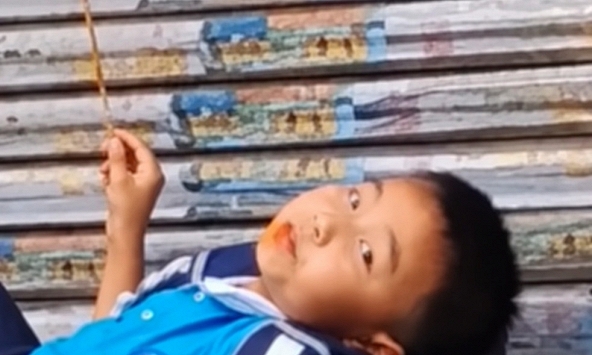 Mẹ đến đón muộn, cậu bé thản nhiên nằm trên bậc thềm ăn đồ ăn: Dân mạng bật cười vì quá chill!